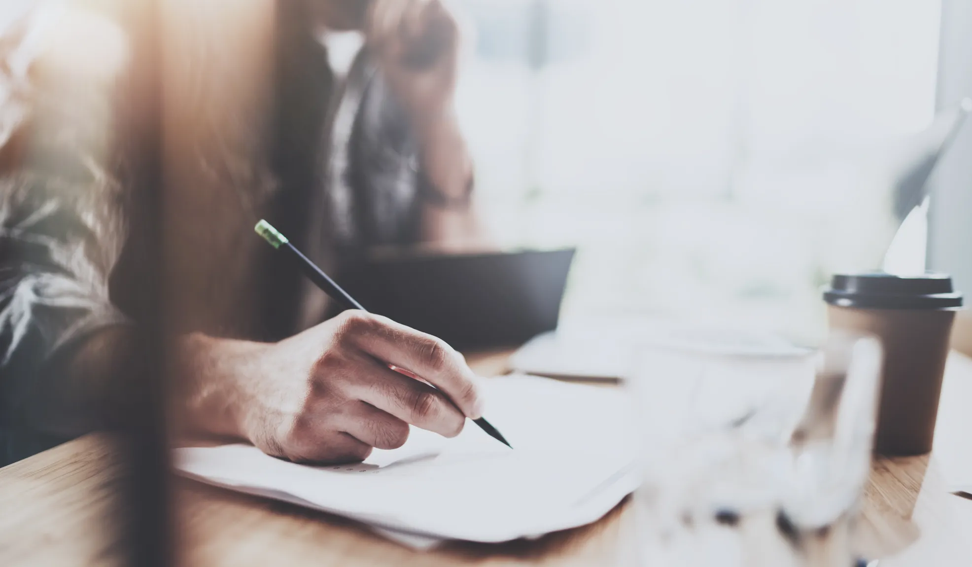 Eine unscharfe Silhouette im Anzug läuft von links nach rechts. Dahinter sitzt ein Mann auf einem Sofa.