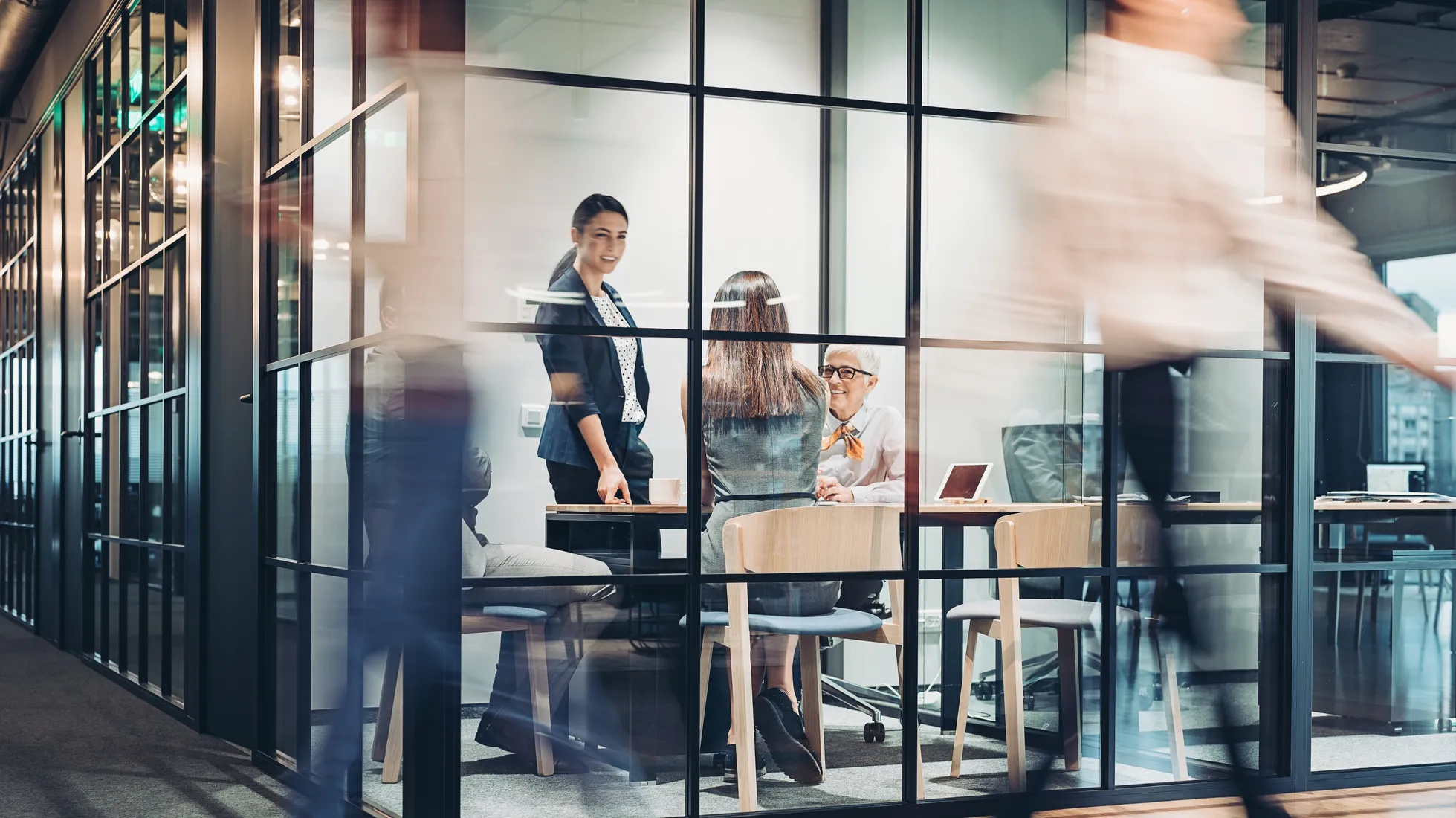 Eine Frau und zwei Männer in einem Besprechungsraum über einen Tisch gebeugt
