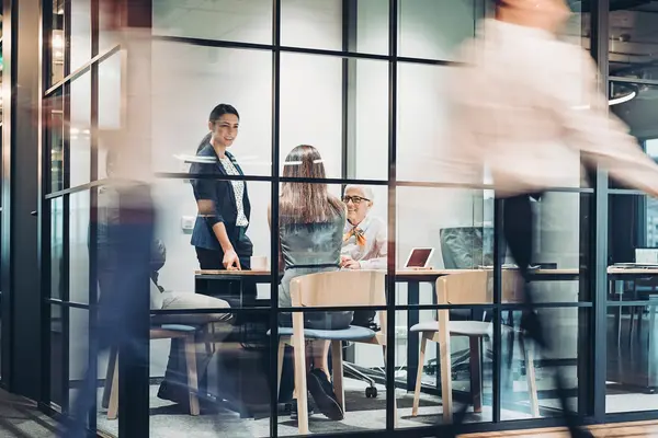 Eine Frau und zwei Männer in einem Besprechungsraum über einen Tisch gebeugt